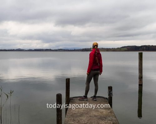 Hiking in canton Zurich, Sophia standing at footpath overlooking a grey Päffikersee