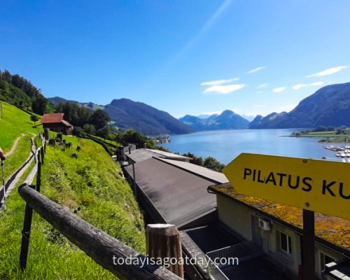 Hiking on Mount Pilatus, yellow Pilatus sign pointing up the street, Lake Lucerne in the backgrouns