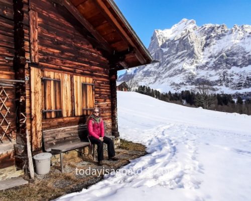 Winter activities in Grindelwald, Sophia sitting outside a wooden mountain hut