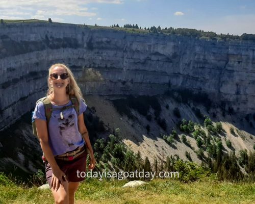 Top Hike in Neuchâtel, blond woman posing in front of the impressive Creux-du-Van rock circus