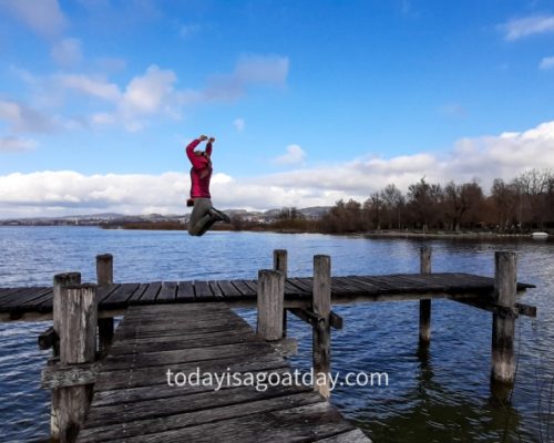 Hiking in canton Zurich, girl jumping up from a landing stage at Pfäffikersee