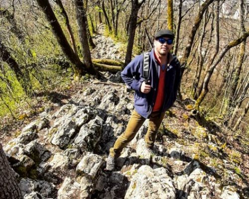 Adventurours hiking in Aargau, a man standing on the Lägern trail looking upwards