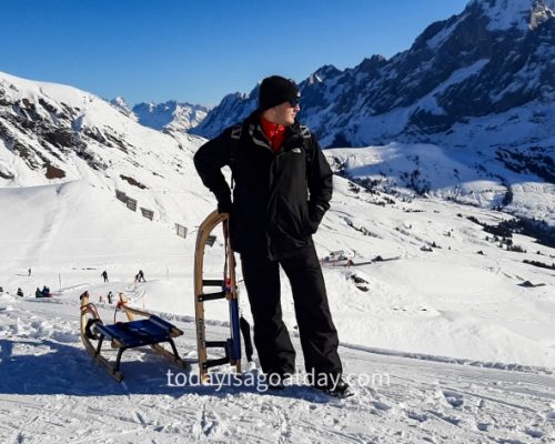 Winter activities in Grindelwald, Krisztian with his sleigh srrounded by alpine panorama