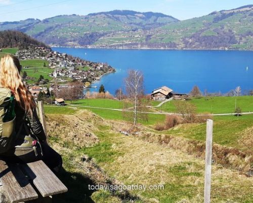 blond girl sitting on bench at view point over Lake Thun on mountain trail