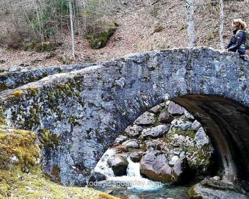 Glarus hiking routes, blond girl sitting on roman saw bridge