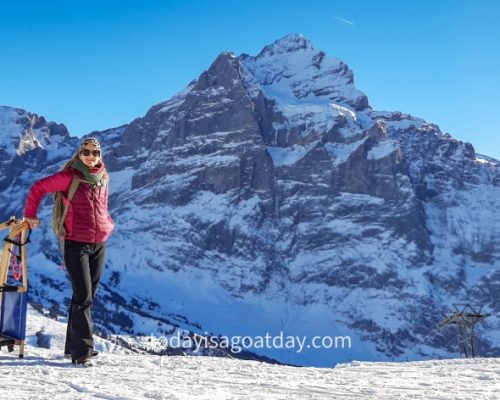 Winter activities in Grindelwald, girl with sleigh, Alpine mountains in the background