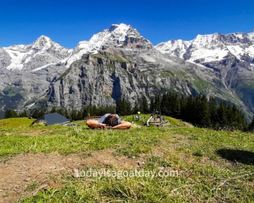 Man lying on his back, resting in Allmendhubel, mountain panorama in the background