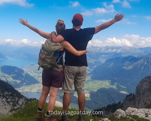 Man and woman with raised hands, cheerfully overlookingg the valley